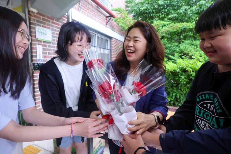 스승의날을 맞이한 15일 서울 노원구 동일초등학교 학생들이 선생님에게 카네이션을 건네며 환하게 웃고 있다. 