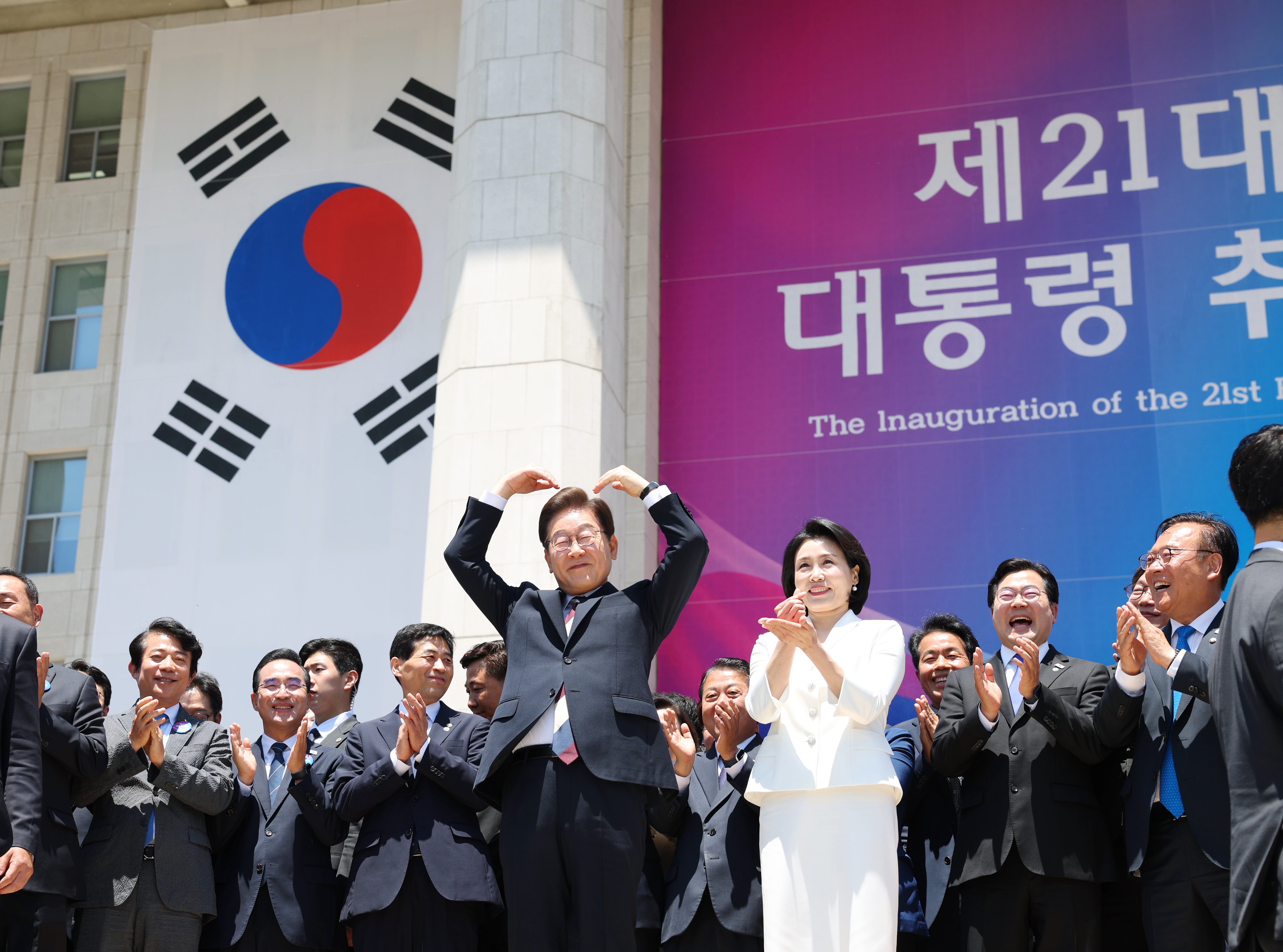 After being sworn in, President Lee Jaemyung (left) on June 4 greets his cheering supporters outside the National Assembly by making a heart gesture alongside first lady Kim Hye-gyeong. Afterward, he went to the hall Sarangjae at the parliamentary building to meet National Assembly Speaker Woo Won-shik and representatives of the ruling and opposition parties to eat bibimbap (spicy rice with vegetables and meat) for lunch before officially beginning his term. 